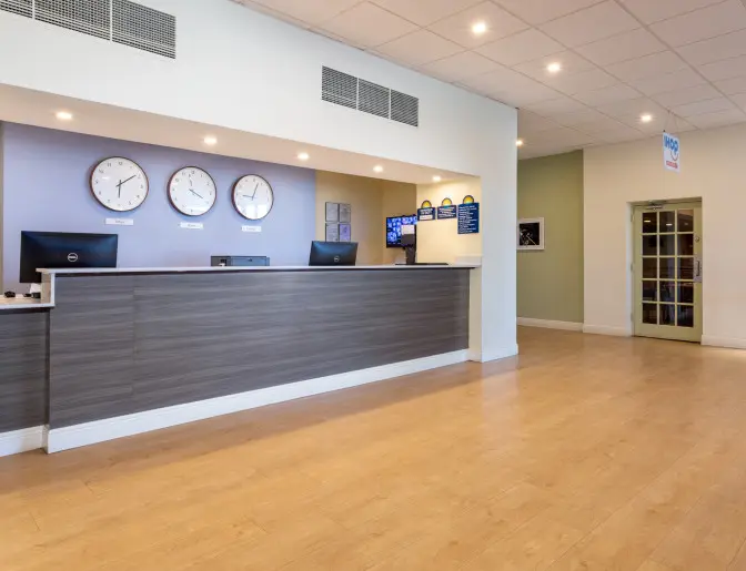 Reception area at the Days Inn Titusville hotel, with a sleek front desk, clocks displaying various time zones.
