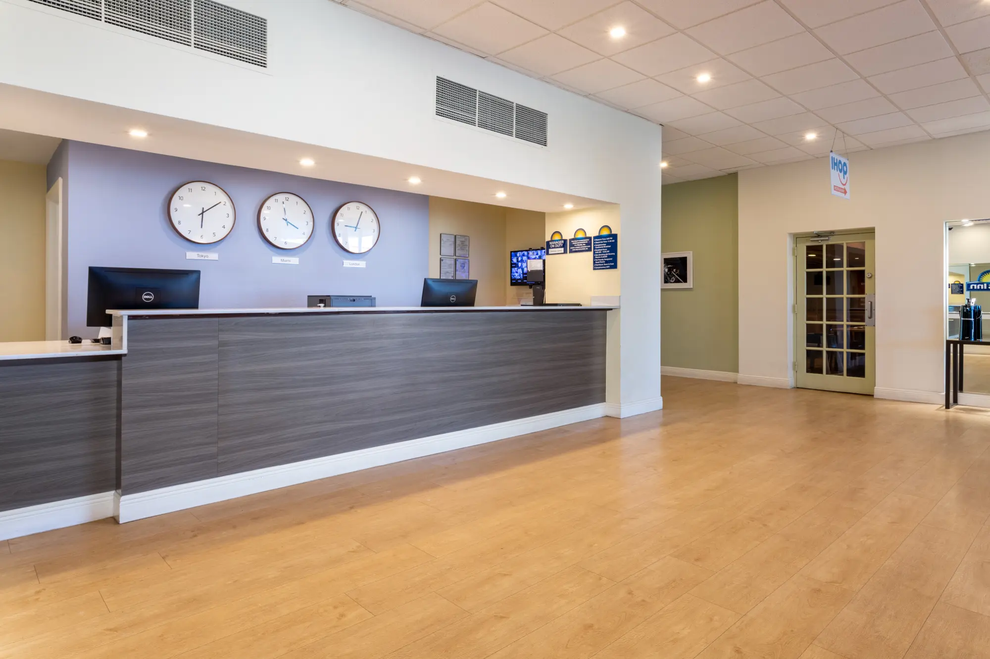 Reception area at the Days Inn Titusville hotel, with a sleek front desk, clocks displaying various time zones.