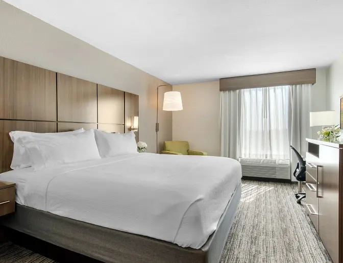 Hotel room at Holiday Inn with a king bed, sleek wooden furniture, and a flat-screen TV opposite the bed.
