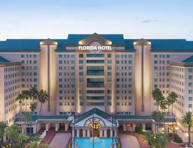 The Florida Hotel exterior, featuring a grand central entrance, palm trees, and soft evening lighting.