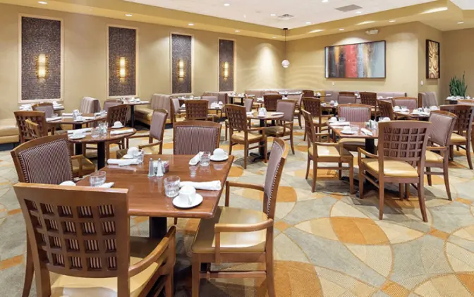 Dining area in the Florid aHotel featuring geometric carpet, brown chairs and square tables.