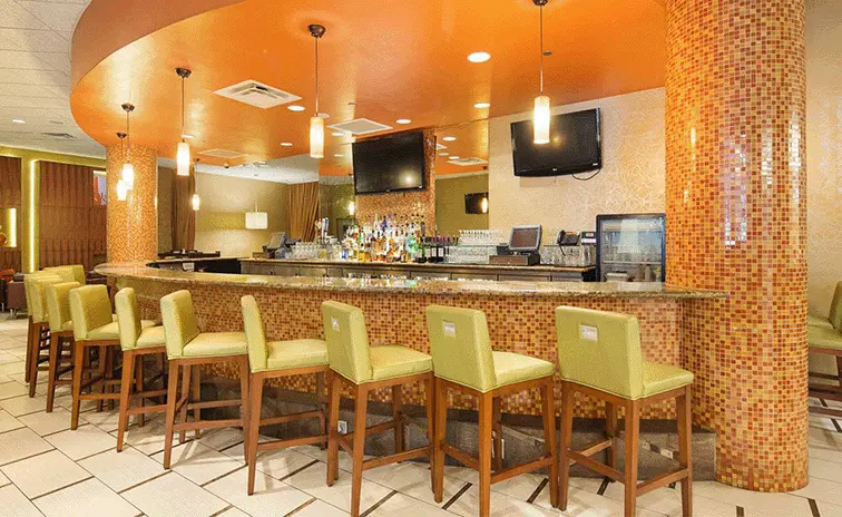 Hotel Bar inside the Florida hotel featuring green high top chairs and a selection of alcohol.