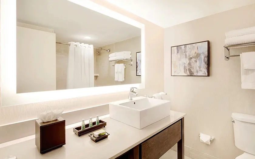 Bathroom inside a guest room at the Florida Hotel featuring a large back lit mirror.