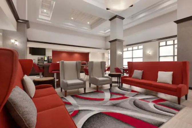 Ramada Suites lobby showcasing contemporary design and plush red seating.