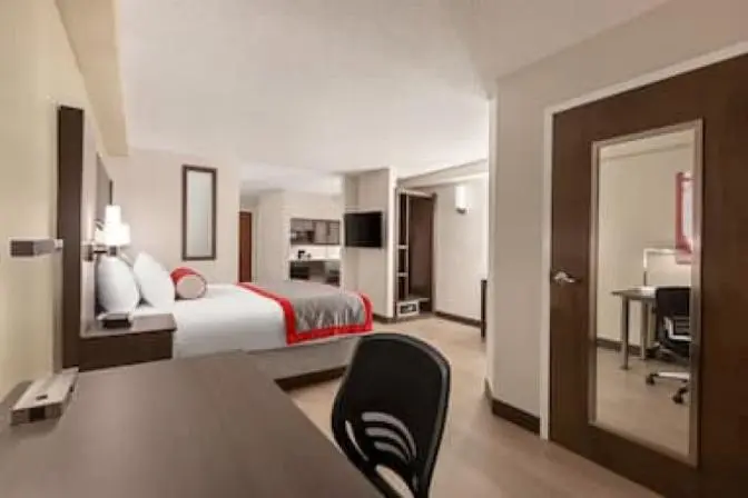 Modern king room at Ramada Suites featuring a comfortable king sized bed a kitchenette and a desk.