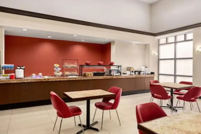 Modern dining area at Ramada Suites featuring elegant seating arrangements, stylish wooden tables, and contemporary lighting fixtures in a well lit space.