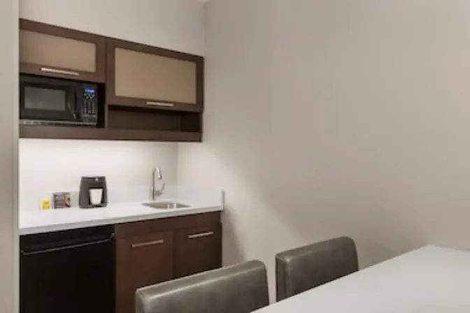 Kitchenette in Ramada Suites queen room featuring a mini refrigerator, microwave, sink and coffee maker.