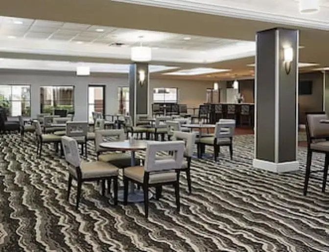 Spacious dining room in Staybridge Suites International Airport Hotel featuring a variety of seating options and contemporary design elements.