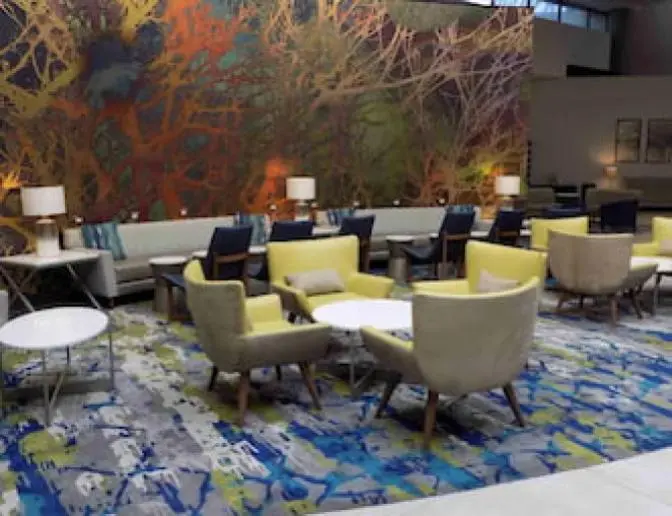 Holiday Inn Orlando International Airport lobby with colorful abstract wall art, comfortable seating areas featuring yellow and beige chairs, and soft lighting.