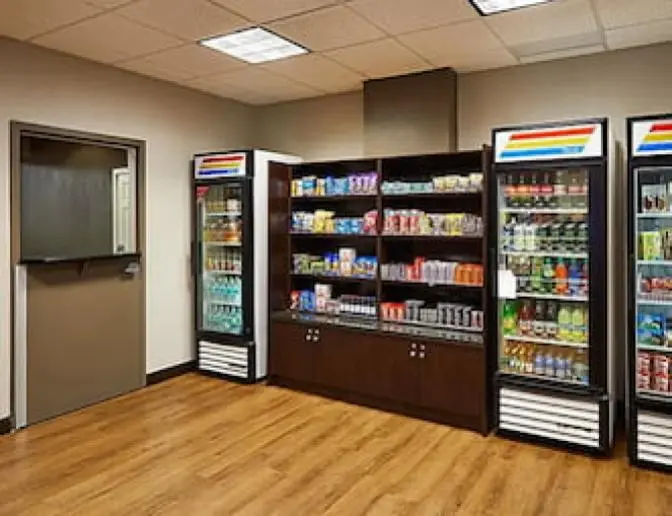 Staybridge Suites Orlando International Airport Hotel market area at Staybridge Suites with refrigerated cases and shelves stocked with snacks, drinks, and toiletries.