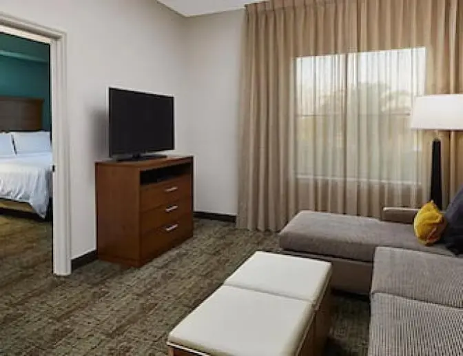 Bedroom featuring a cozy living area with a sofa and TV, and a separate bedroom with two queen beds.