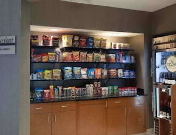 The Market at SpringHill Suites by Marriott featuring shelves stocked with a variety of snacks, chips, candies, and a refrigerated section with drinks and wines.
