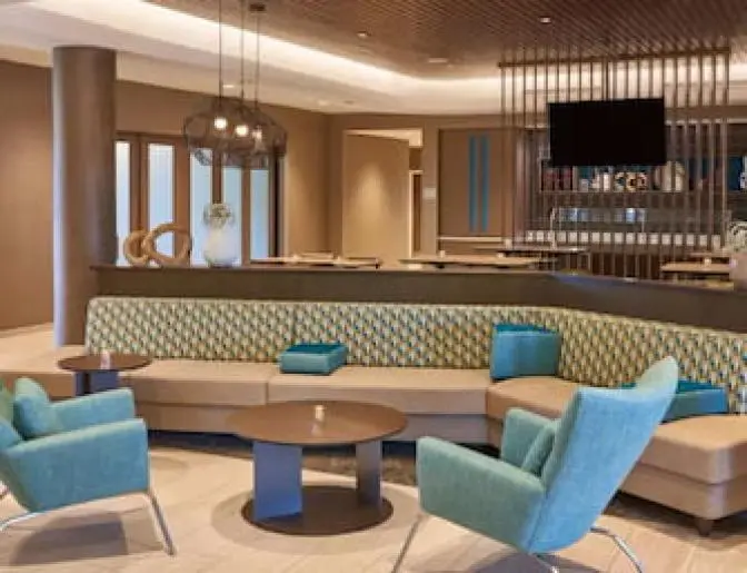 Comfortable seating area in the SpringHill Suites Lake Nona lobby, with bright blue chairs, a patterned sofa, and wooden decor elements creating a cozy yet stylish atmosphere.