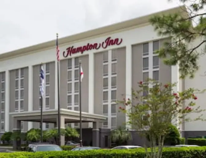 Exterior view of Hampton Inn Orlando International Airport Hotel with American and state flags at the entrance.