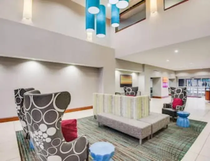 Modern lobby at Residence Inn by Marriott with comfortable seating including patterned armchairs, a striped sofa, blue pendant lighting, and a contemporary design.