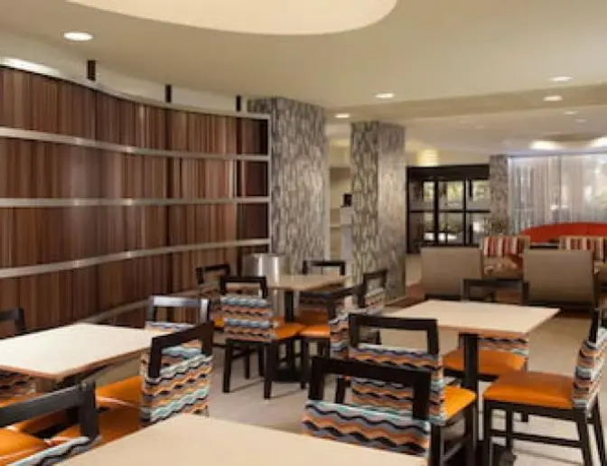 A stylish dining area with a combination of tables and chairs, featuring colorful patterned upholstery and a wood-paneled curved wall.