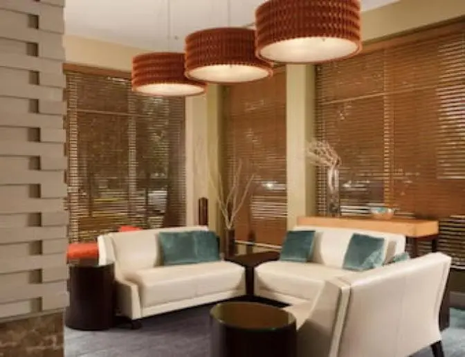 Hilton Garden Inn Orlando Airport Hotel lobby featuring white leather couches with teal pillows, wood accent tables, and unique woven pendant lights.