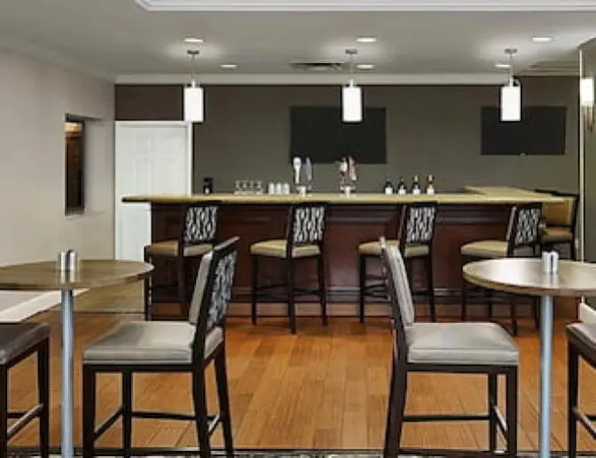 Elegant hotel bar, including high top seating, bar stools, and contemporary decor.