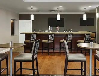 Elegant hotel bar, including high top seating, bar stools, and contemporary decor.
