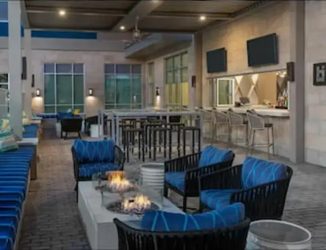 Spacious covered outdoor patio and bar featuring firepits and comfortable blue couches and chairs.
