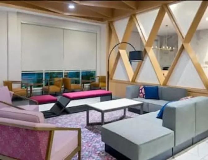 Hyatt House Hotel near Orlando International Airport lobby sitting area featuring modern decor with a large grey couch and comfortable pink seating.