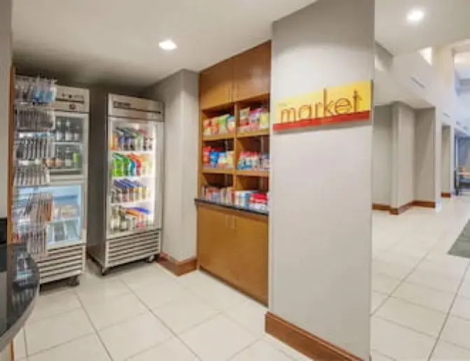The Market at Residence Inn by Marriott featuring refrigerated display cases with beverages, shelves stocked with snacks, and a modern design.
