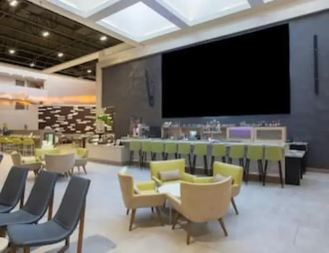 Holiday Inn Orlando International Airport bar and restaurant with comfortable armchairs, coffee tables, and a vibrant color scheme.