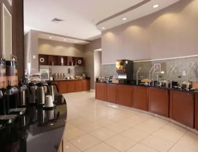 Breakfast buffet area at SpringHill Suites by Marriott featuring a variety of hot and cold food stations, beverage dispensers, and coffee machines on a polished counter.