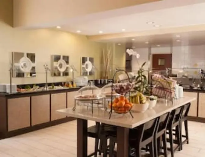 Hilton Garden Inn Orlando Airport Hotel breakfast buffet with a variety of fresh fruits, pastries, and cereals displayed on a central island.