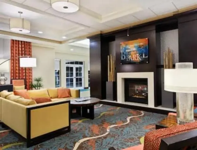 Bright colorful sitting area in the lobby of Homewood Suites by Hilton near Orlando Airport featuring a bright yellow couch and vibrant carpeting.