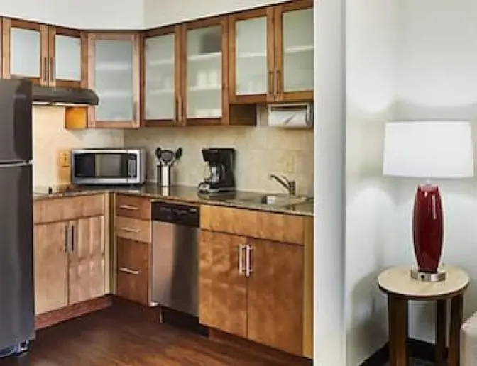 Hotel room kitchenette with stainless steel appliances, wooden cabinets, a microwave, and a coffee maker.