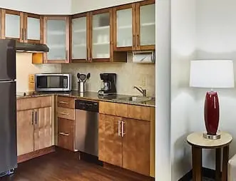 Hotel room kitchenette with stainless steel appliances, wooden cabinets, a microwave, and a coffee maker.