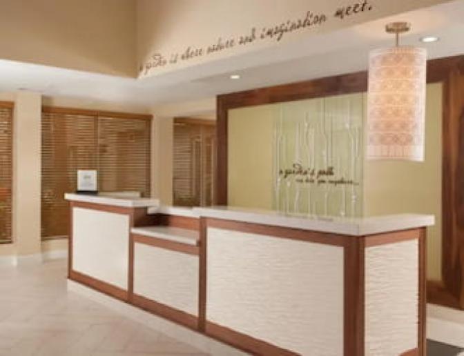 Lobby of Hilton Garden Inn Orlando Airport Hotel showcasing a reception counter and decorative elements with a quote on the wall.