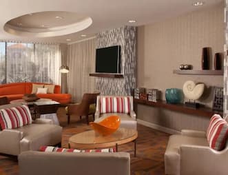 Contemporary lobby at Hampton Inn Orlando International Airport Hotel featuring a round orange sofa, armchairs with striped pillows, and modern decor elements.