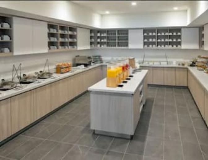 Self serve breakfast bar featuring hot food options and an island in the middle of the room that holds all the cold juices. that are offered.