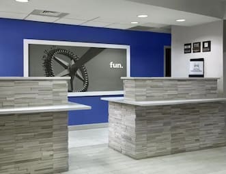 Hampton Inn Orlando International Airport Hotel lobby featuring two modern reception desks with a blue wall and artwork in the background.