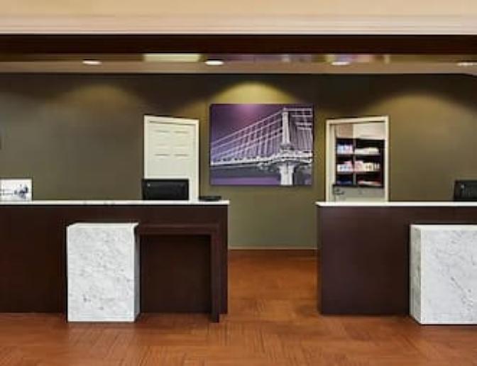 Reception area in the Staybridge Suites Orlando International Airport Hotel lobby, showcasing two desks with marble accents and a painting in the background.