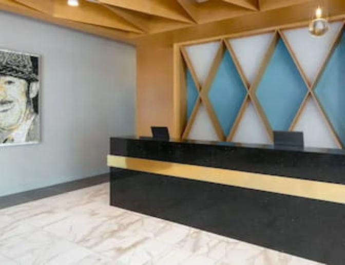 Modern check in desk featuring black marble countertops and a blue diamond geometric artwork hanging on the wall.