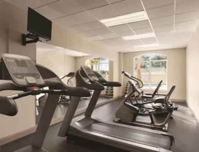 Gym featuring cardio equipment with a view of the outdoor swimming rool.