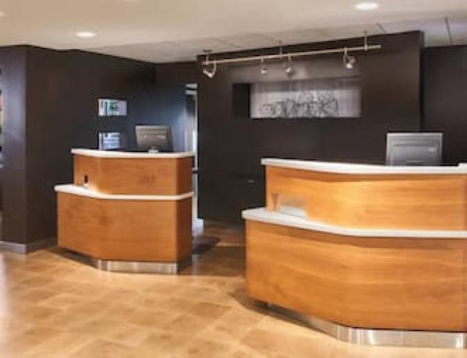 Front desk area of the Courtyard by Marriott hotel lobby, showcasing two sleek wooden reception counters.