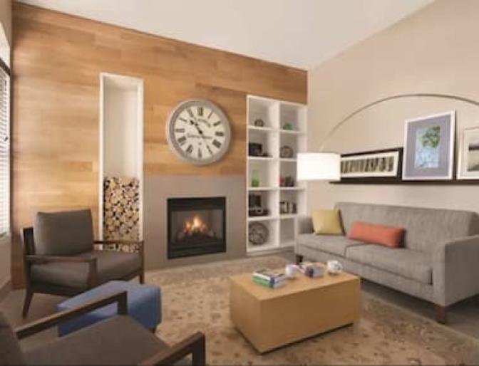 Warm and cozy lobby inside Country Inn & Suites near Orlando Airport featuring a fireplace and comfortable seating arera.