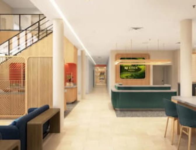 Lobby area at EVEN Hotel highlighting a modern reception desk with green paneling, adjacent self-serve market, vibrant lounge seating, and a staircase with wood panel dividers and open mezzanine above.
