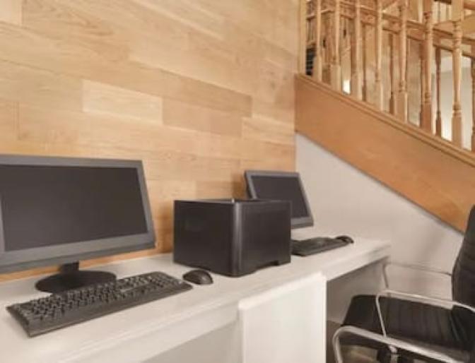 Two workstations and a printer on top of a white desk next to a wooden staircase inside .Country Inn & Suites near Orlando Airport.
