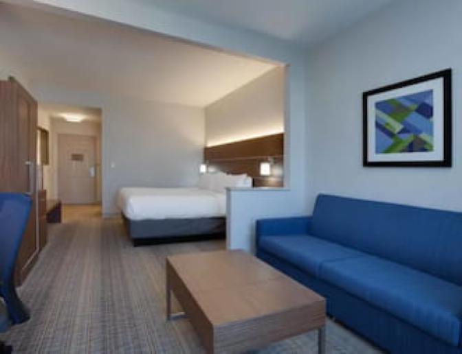 A room that has one King bed and a large blue couch at the Cambria Orlando International Airport hotel.