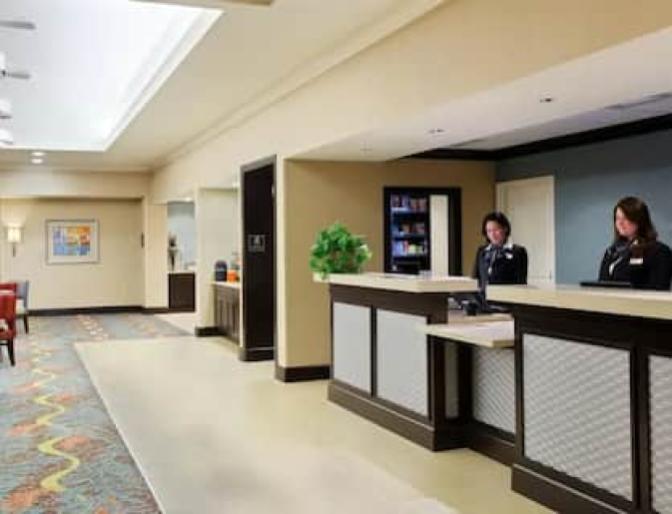 Front desk check in inside Homewood Suites by Hilton near Orlando Airport featuring two large check in desks.