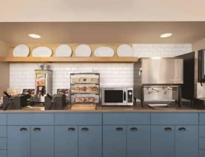 Buffet style self serve breakfast items atop blue cabinets in the dining area of Country Inn & Suites near Orlando Airport.