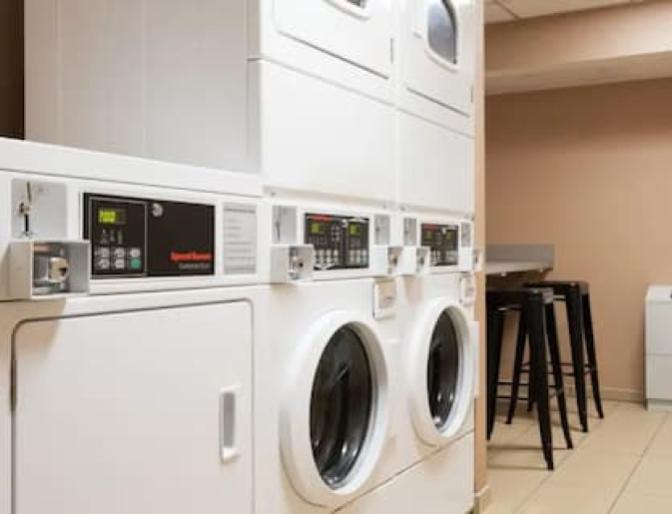 Laundry room inside Homewood Suites by Hilton near Orlando Airport featuring multiple stacked washing machines and dryers.