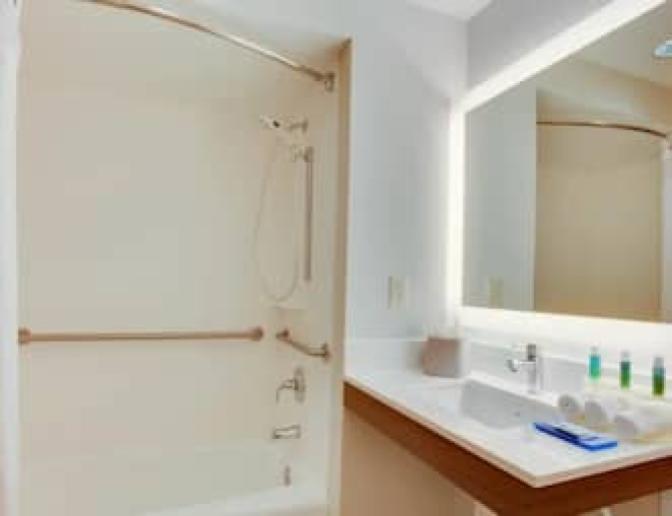 Bathroom inside of a bedroom featuring a large backlit mirror.