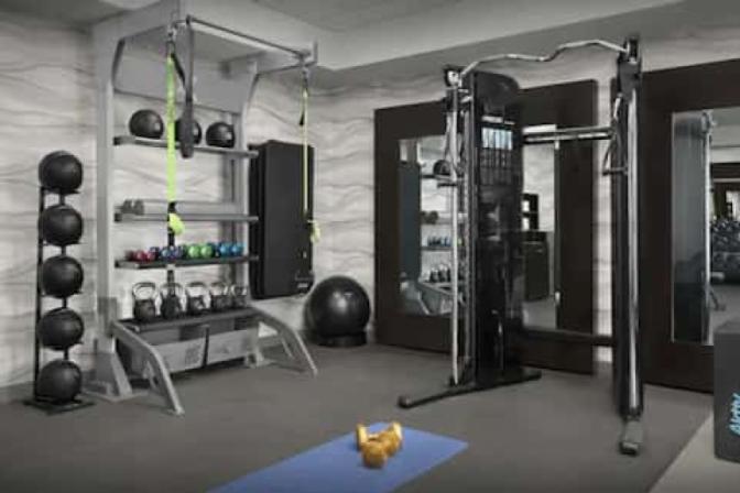 Spacious bright gym inside Homewood Suites by Hilton near Orlando Airport featuring cardio gym equipment and weightlifting equipment.