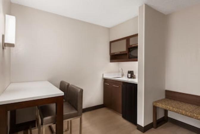 Kitchenette in Ramada Suites king room featuring a mini refrigerator, microwave, sink and coffee maker.